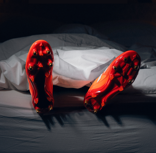 A dark image of a person in bed wearing rugby boots